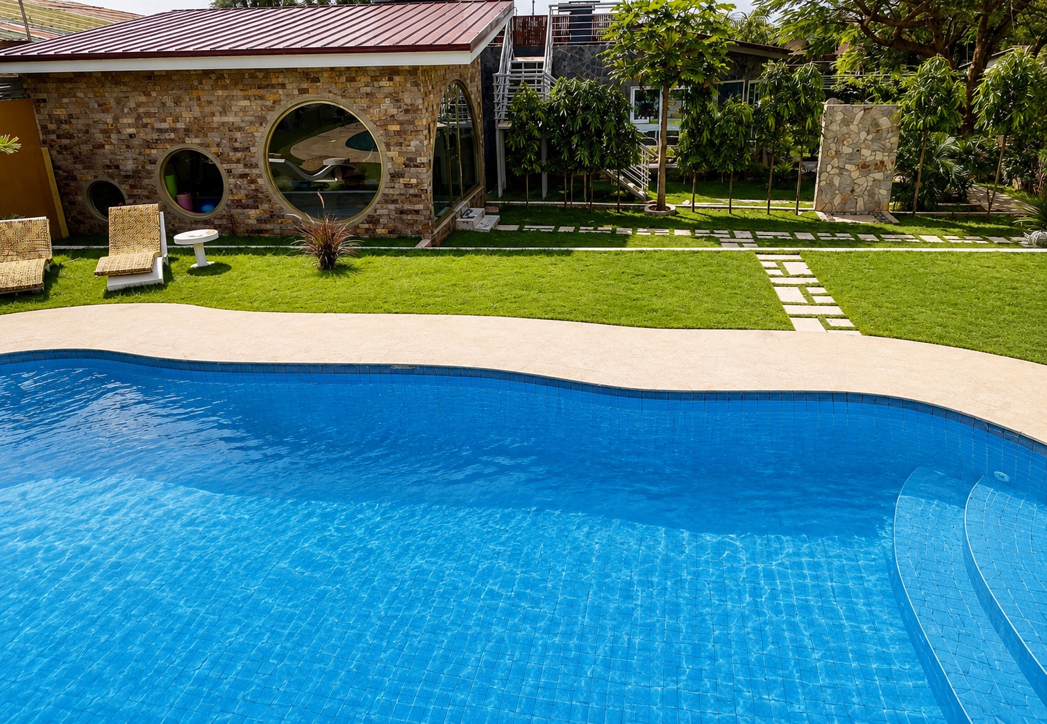 Main pool in daylight with the stone gym pavilion and lawn behind