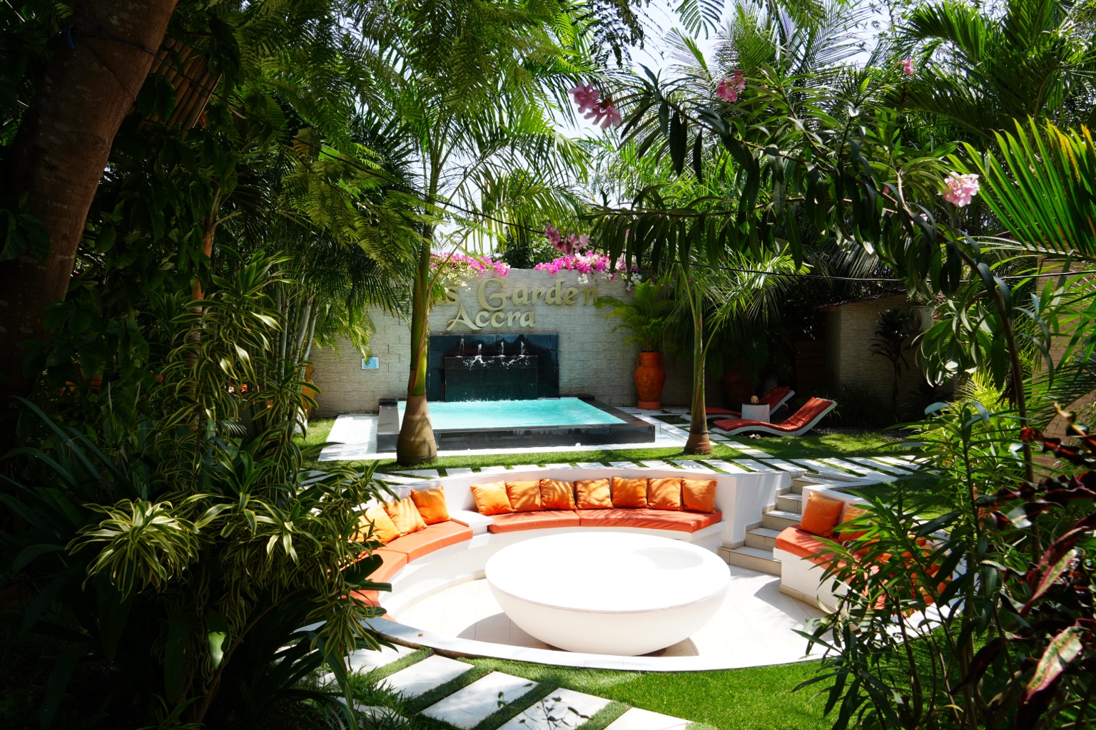 Sunken lounge with fountain wall framed by tropical planting