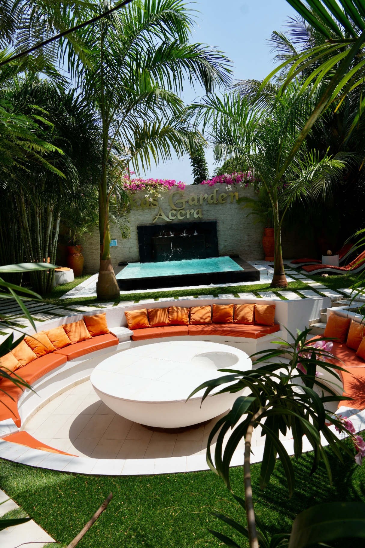 Pool court head-on with palms and water wall