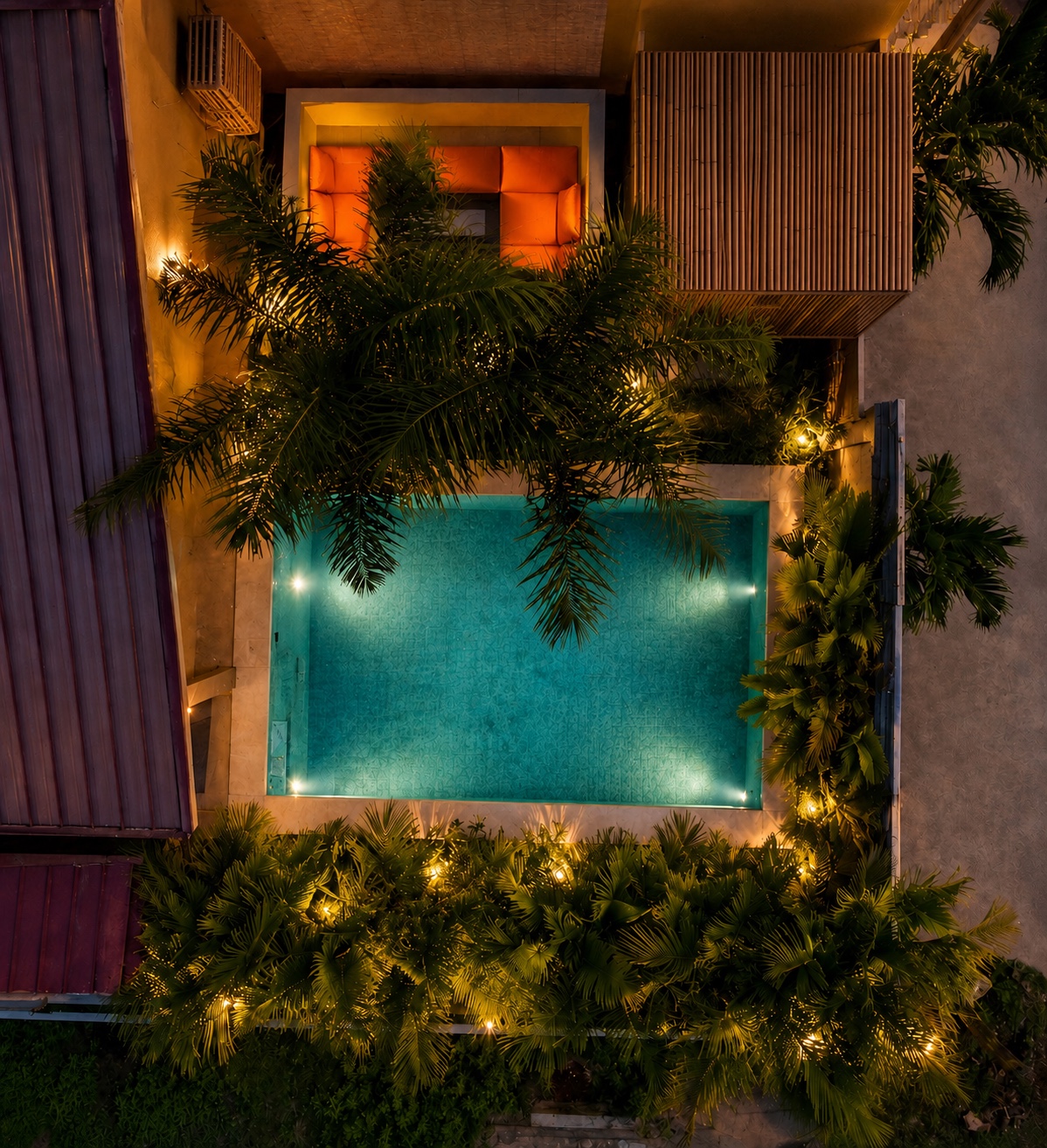 Aerial view of a private pool and terrace lit at dusk