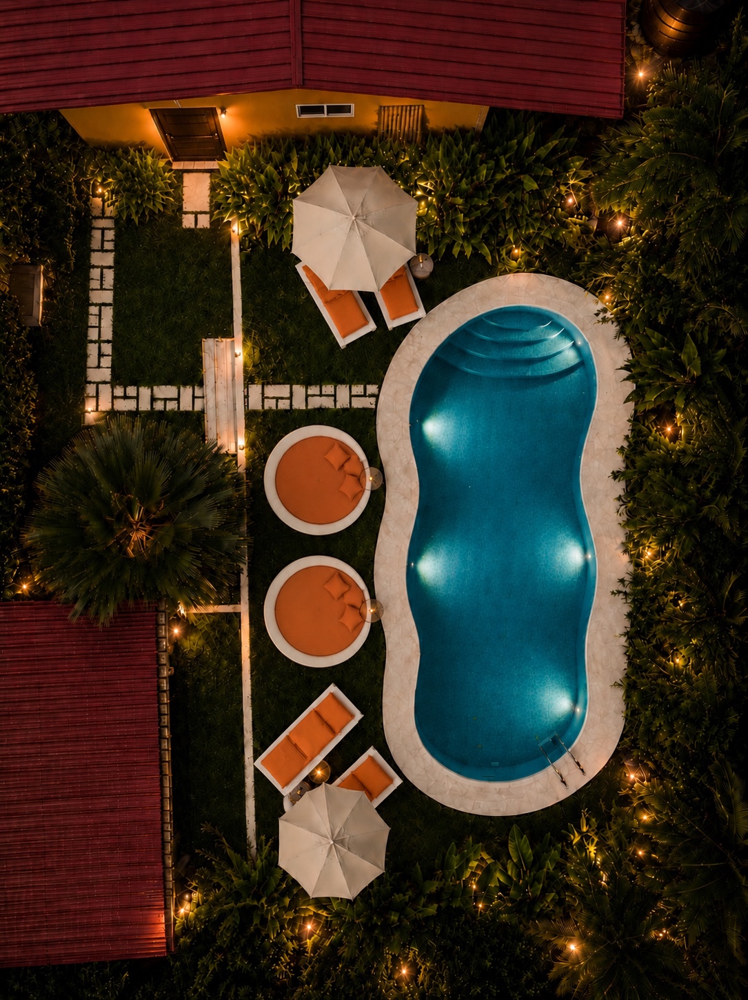 Aerial view of the main pool with loungers and garden lights at night