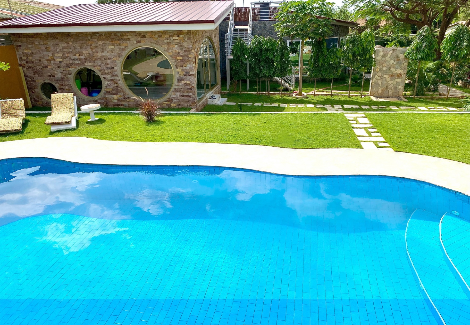 Curved pool with turquoise water and stone villa in daylight