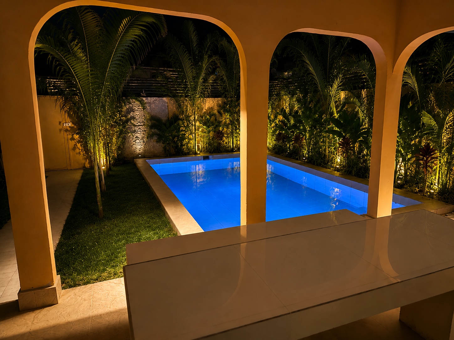 Private pool seen through the arched terrace at night