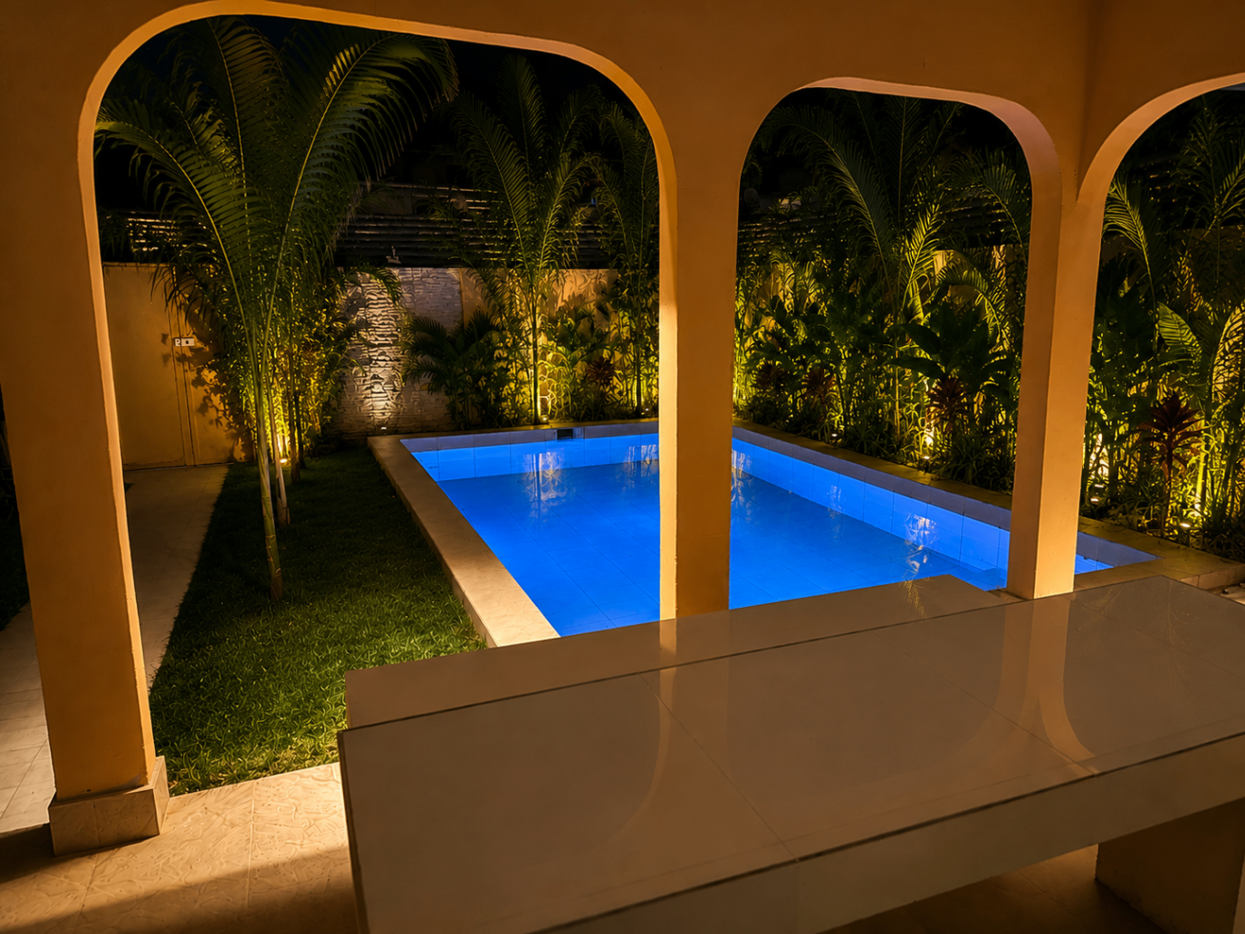 Night pool framed by villa arches and palms